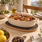 Dark oval cork trivet supporting a hot serving dish in a bright Mediterranean kitchen setting